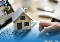 a person typing on a laptop and a miniature of a house